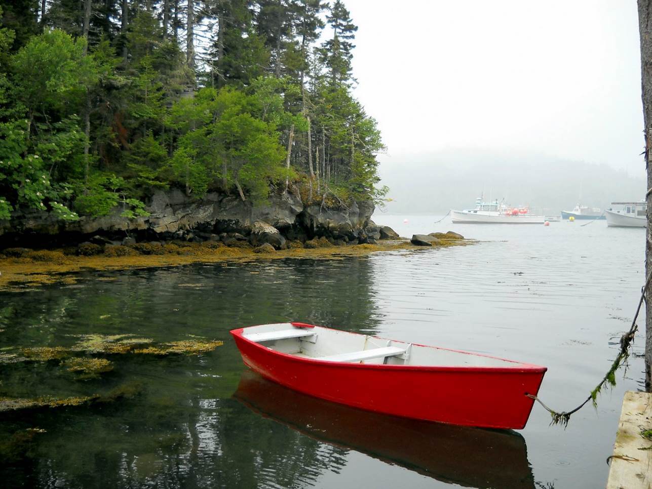 Red rowboat in a river that opens into a bay