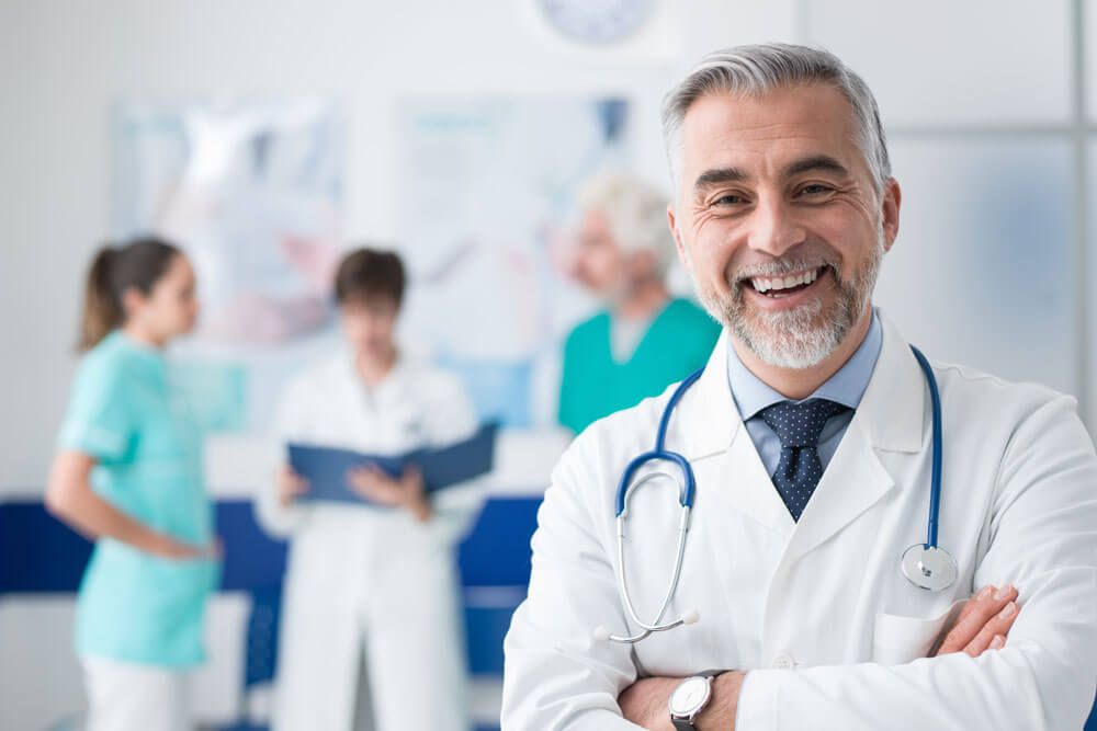 Smiling doctor with other medical professional in the background