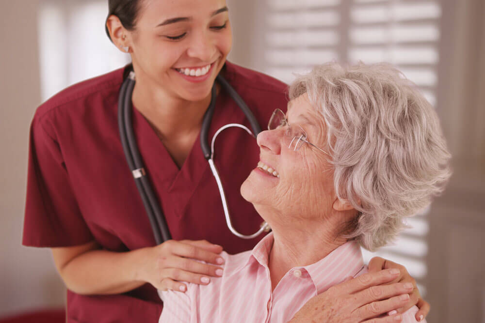 Nurse embracing elderly woman.