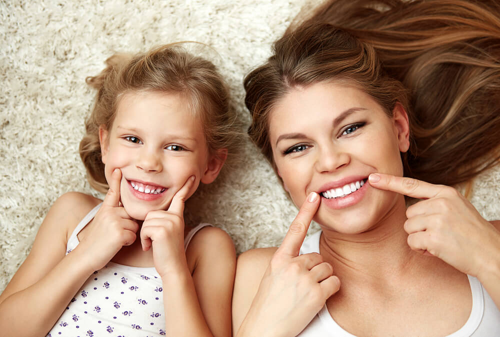 mother and daughter showing off their healthy smiles